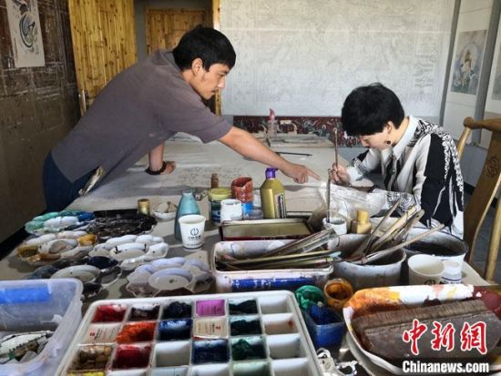 圖為2020年8月下旬，敦煌“80后”畫家張杰龍(左)在為云南麗江“學(xué)生”莫北講解敦煌壁畫的繪畫技巧。　馮志軍 攝