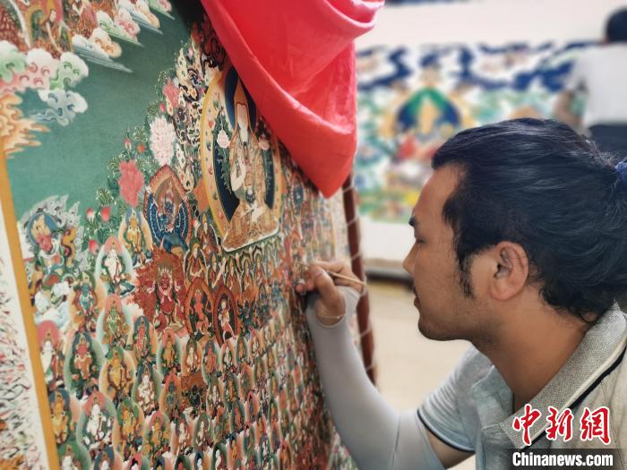 圖為更登才讓的徒弟繪畫唐卡?！?zhí)砀?攝