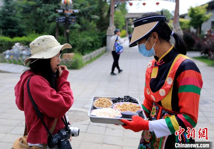 圖為身穿土族服飾的女性介紹當(dāng)?shù)靥厣〕浴！⊙Φ?攝