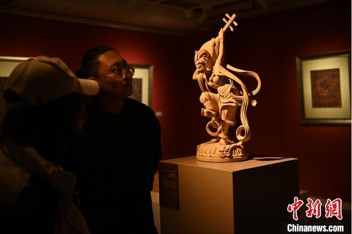 圖為季茂杰向參觀者介紹自己創(chuàng)作敦煌木雕的過程。李亞龍 攝</p>
<p>