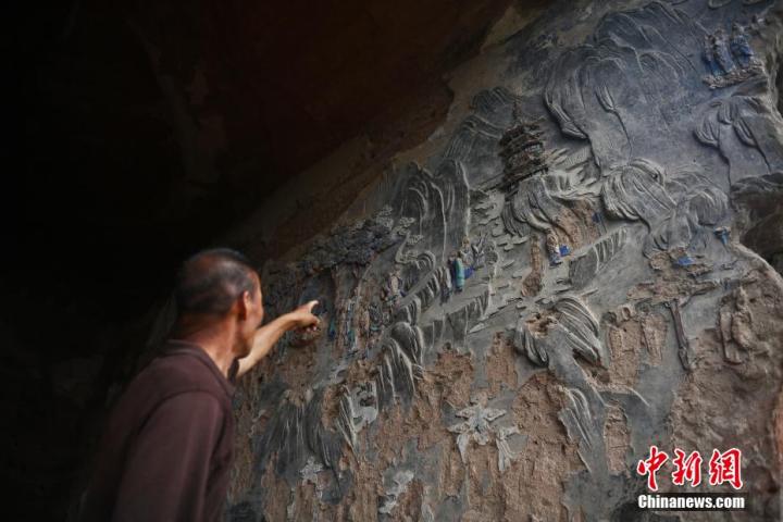 7月15日，甘肅省平?jīng)鍪袥艽h百里石窟長(zhǎng)廊羅漢洞石窟內(nèi)，該窟文保員郭建平介紹窟內(nèi)石刻彩繪壁畫(huà)。郭建平家中三代人曾自發(fā)保護(hù)羅漢洞石窟。羅漢洞石窟遺存40余個(gè)窟龕，以北魏至清代風(fēng)格為主。中新社記者 李亞龍 攝