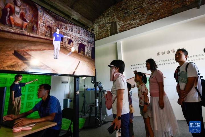 7月22日，游客體驗(yàn)“尋境敦煌——數(shù)字敦煌沉浸展”后，在虛擬演播廳拍攝一段真人與洞窟虛擬場(chǎng)景交互的視頻。新華社記者 郎兵兵 攝</p>
<p>