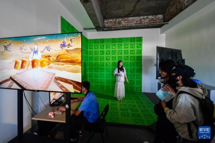 7月22日，游客體驗(yàn)“尋境敦煌——數(shù)字敦煌沉浸展”后，在虛擬演播廳拍攝一段真人與洞窟虛擬場(chǎng)景交互的視頻。新華社記者 郎兵兵 攝</p>
<p>